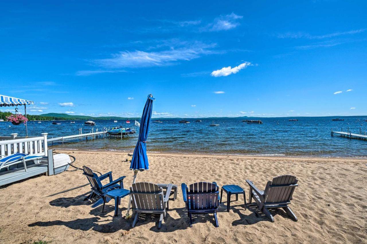 a group of chairs and an umbrella on the beach at Beachfront Sebago Cottage with Deck and Grill! in North Sebago