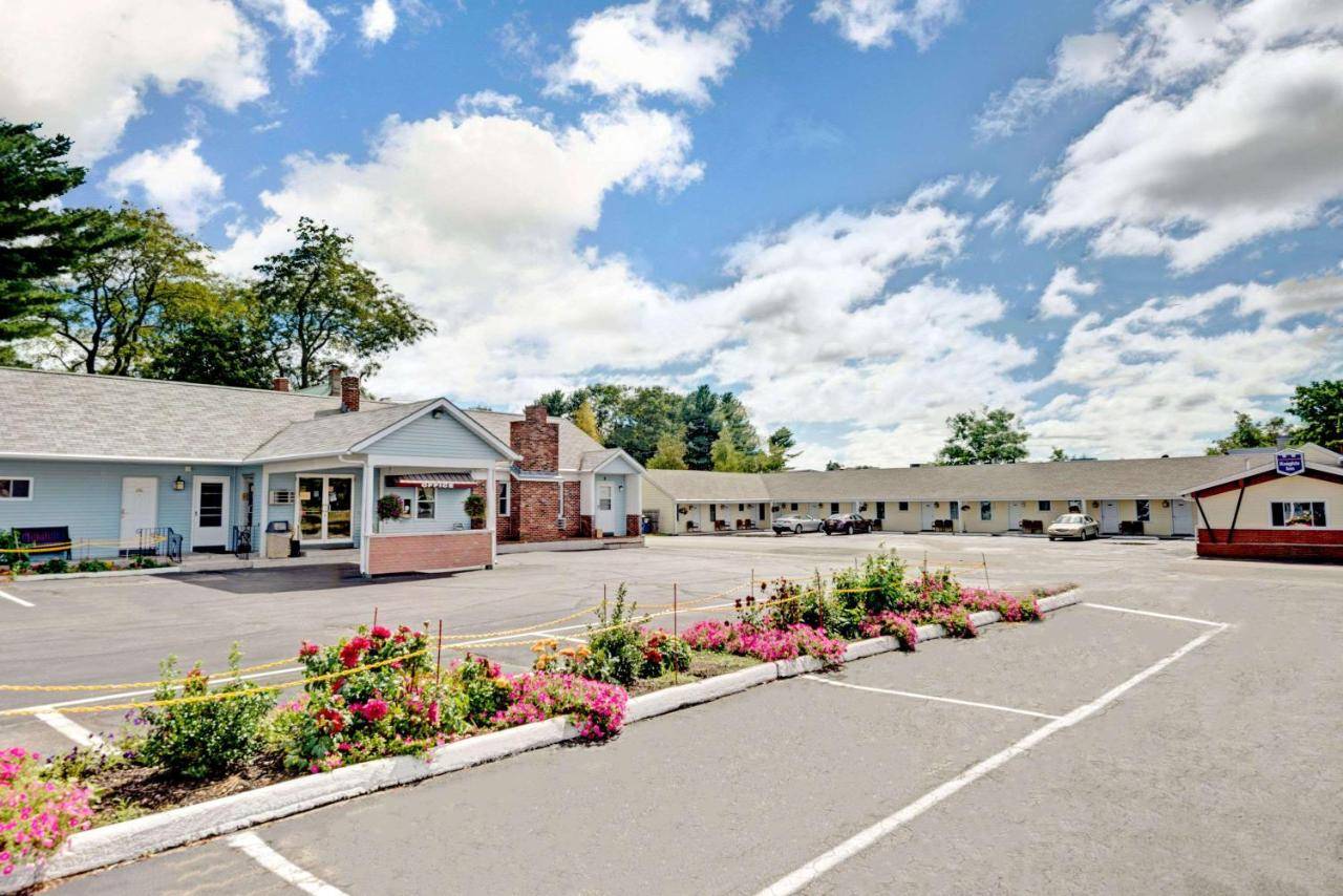 a parking lot in front of a building with flowers at Budget Inn in South Portland