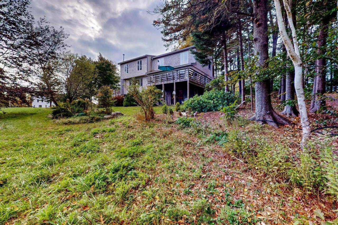a large house on a grassy hill with trees at Clarkside at Cobb Nob in Southwest Harbor