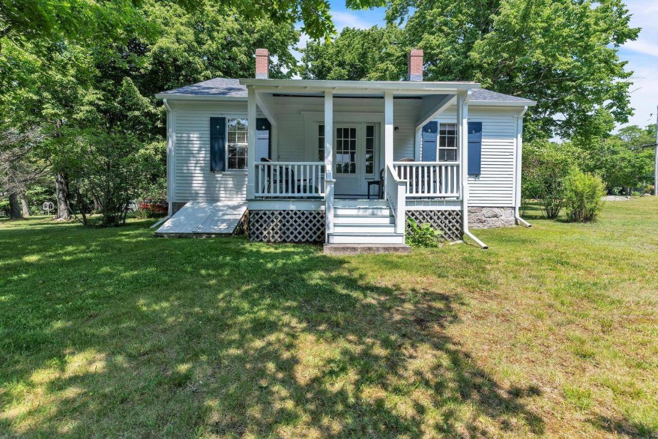 a small white house with a porch on a lawn at Rustic Farmhouse home in Southwest Harbor