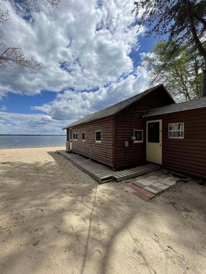 a small building on a beach with the water at LIMBERLOST LIMIT 6 cottage in Standish