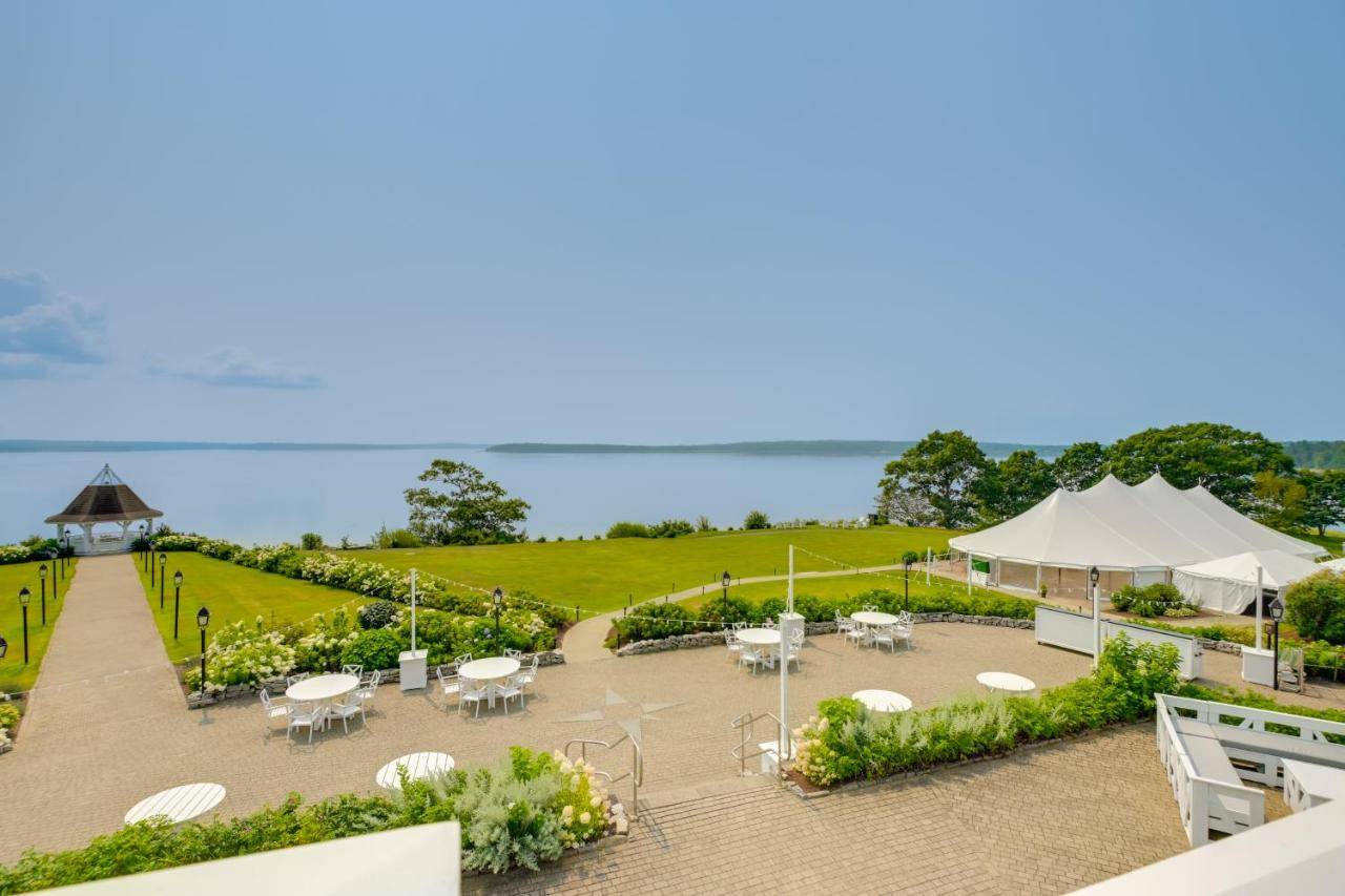 an outdoor patio with tables and white umbrellas at Elegant Oceanfront Maine Estate with Gazebo in Stockton Springs
