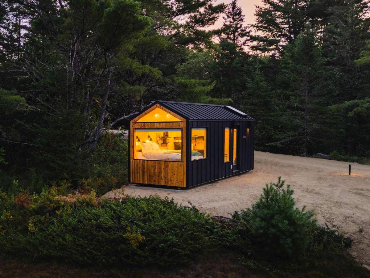a black tiny house sitting on top of a field at Aurora Nook-Cabin with Shower & Queen Bed in Sullivan