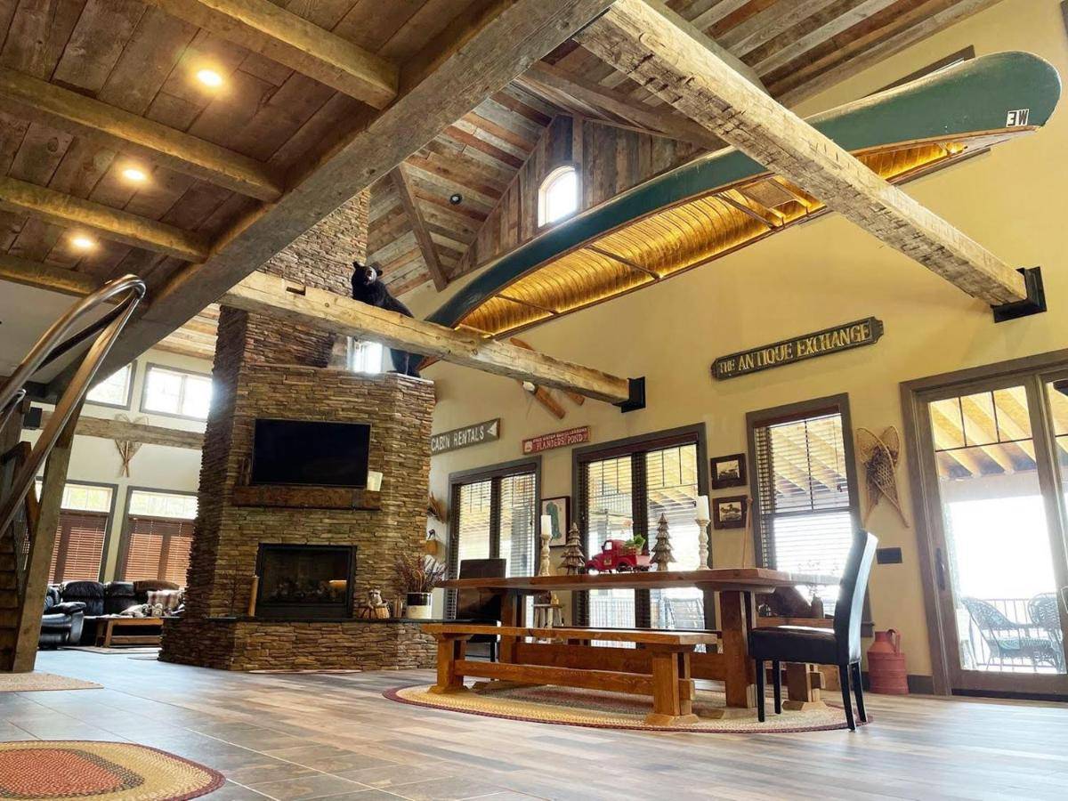 a living room with a table and a fireplace at Downeast Sunset Luxury Lakehouse in Sullivan