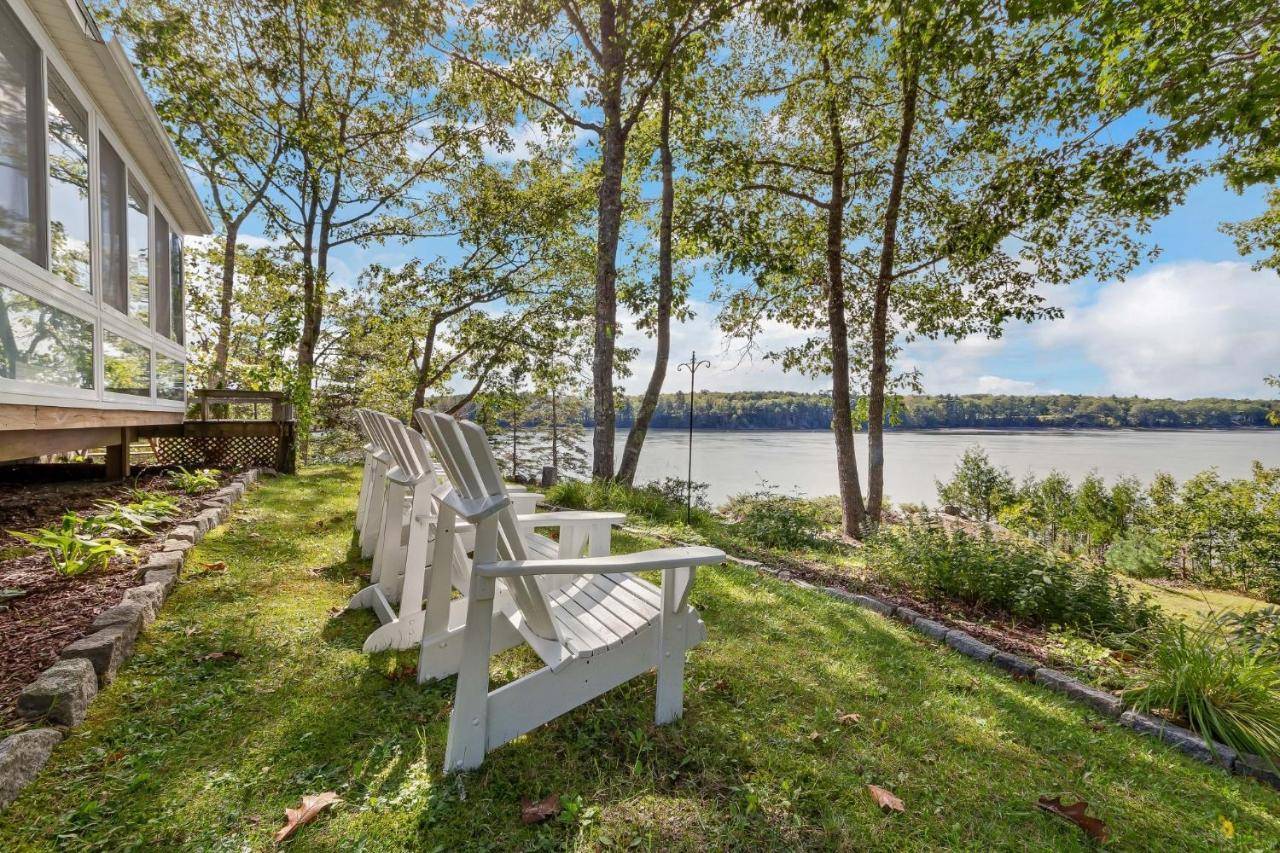 two white chairs sitting on the grass next to a house at JCR Taunton Bay Hideaway home in Sullivan