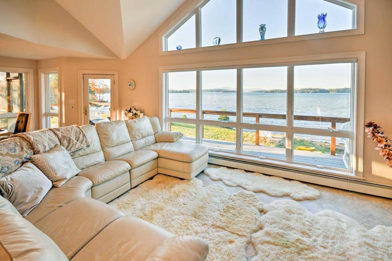 a living room with a couch and a large window at Luxurious Oceanfront Flanders Bay Home with Kayaks! in Sullivan