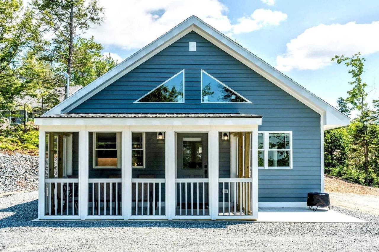 a blue house with a white front porch at Pet-Friendly Lakeside Cabin with Fire Pit & Screened Porch near Flanders Pond in Sullivan, Maine in Sullivan