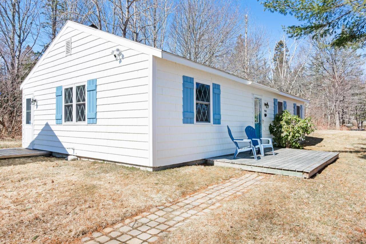 a white house with a chair on a porch at Lucky Stone Cottage in Tremont