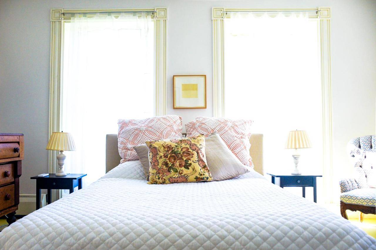 a bedroom with a bed with pillows and two windows at The Waldoboro Inn Room 1 in Waldoboro