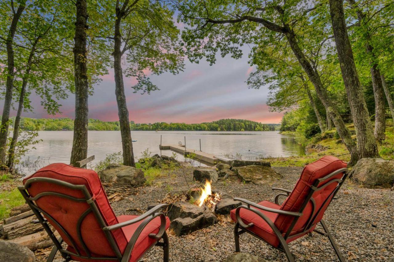 two chairs sitting next to a campfire next to a lake at Your Trail's End in Maine in Wayne