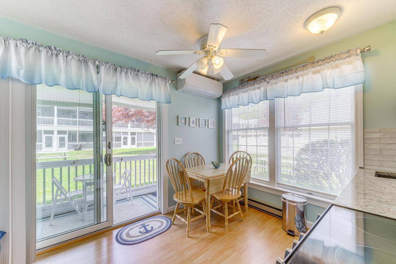 a dining room with a table and chairs and windows at 2 Mi to Drakes Island Beach Condo with Porch! in Wells