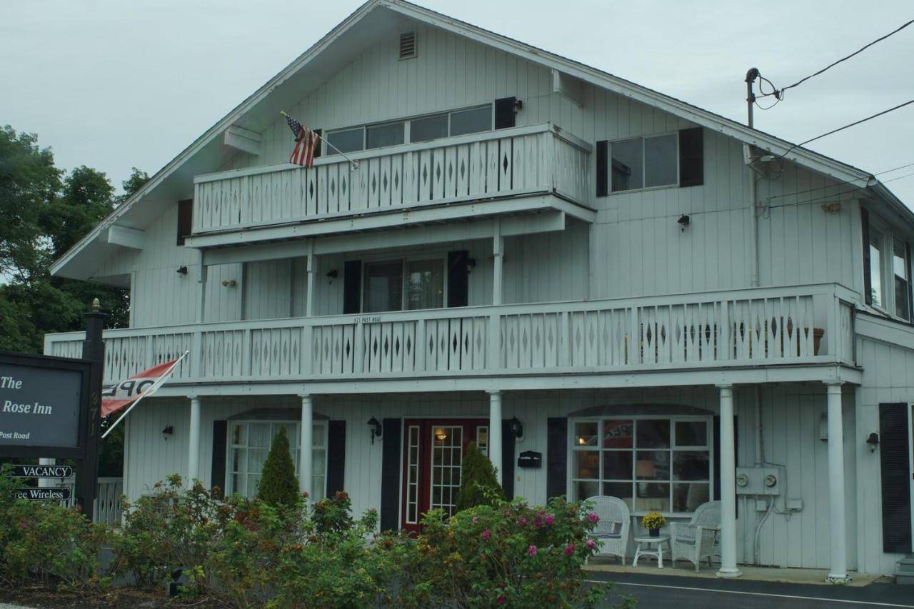 a large white house with a porch and balcony at The Beach Rose Inn in Wells