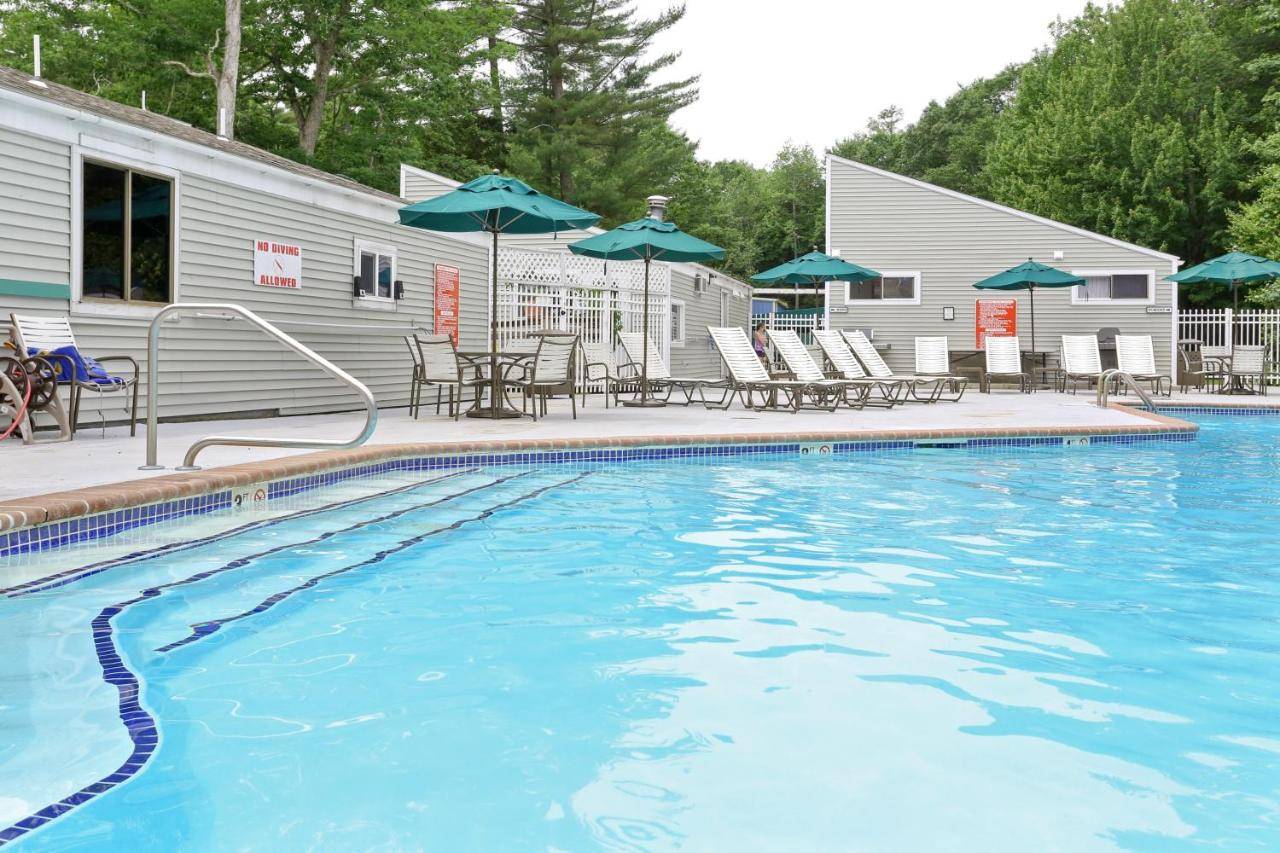 a swimming pool with tables and chairs and umbrellas at Moody Beach Camping Resort Cottage - Loft in Wells