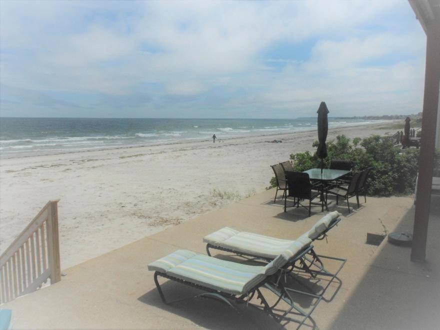 a patio with a table and chairs on the beach at Sea Breeze W007 Wonderful Beachfront Oceanfront property for the whole family 1897 in Wells