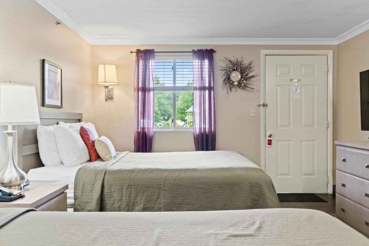 a bedroom with two beds and a window with purple curtains at Sea Mist Resort Motel in Wells
