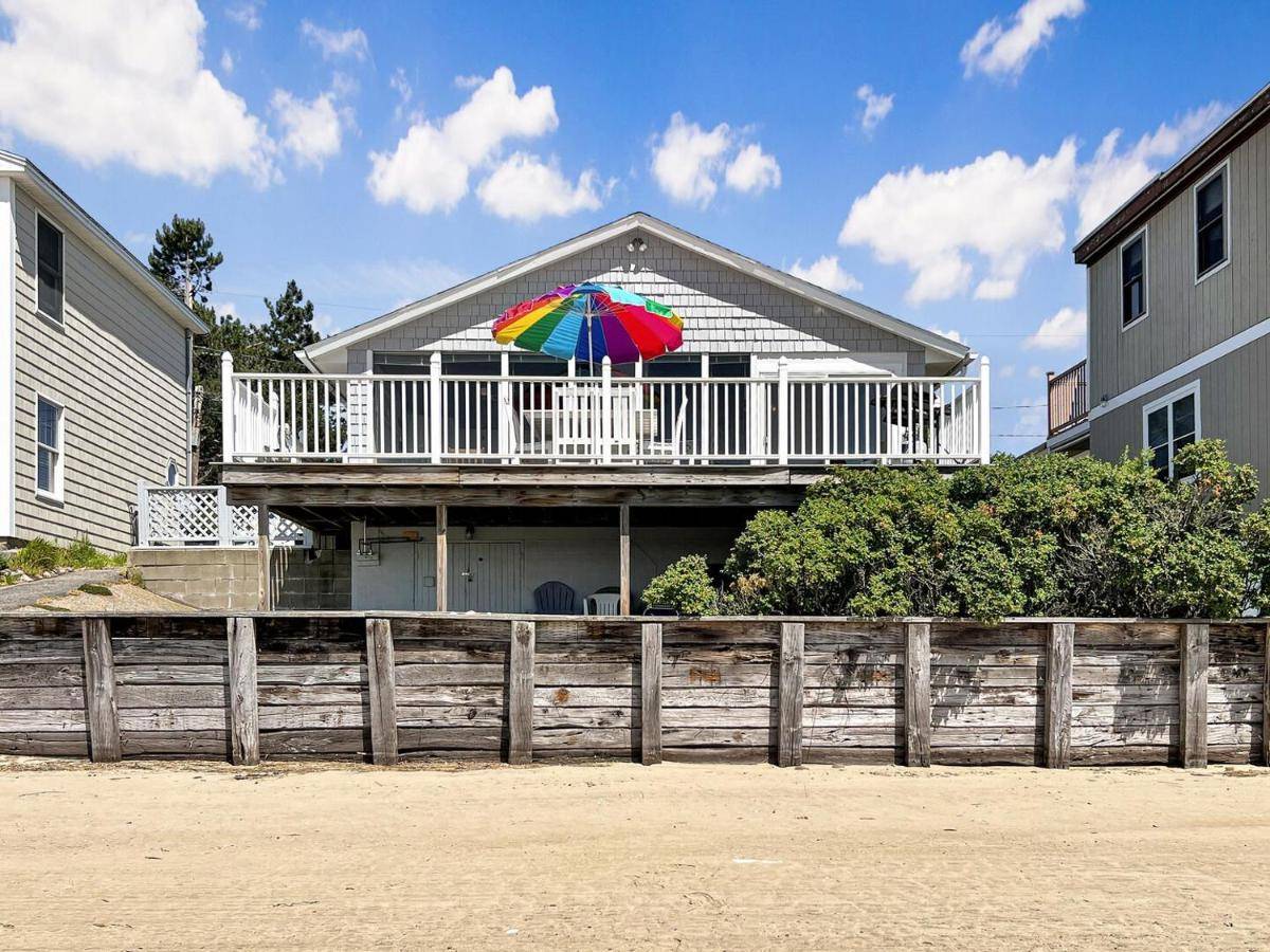a house with a balcony with a colorful umbrella at Twin Sails Cozy Atlantic Ave Retreat in Wells in Wells