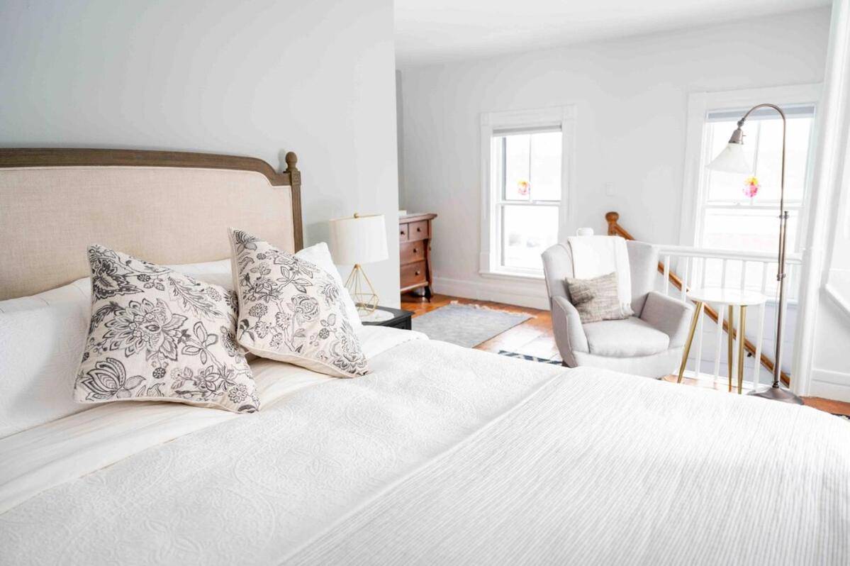 a bedroom with a white bed with pillows and a chair at Retreat at Sea Cloud Cottage in Historic Wiscasset in Wiscasset