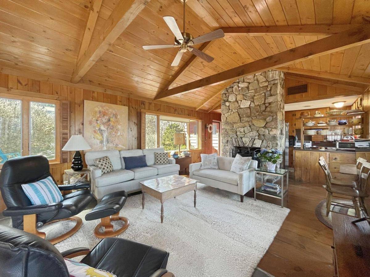 a living room with a ceiling fan and a stone fireplace at Seacoast Sanctuary Warm and inviting cottage with uninterrupted oceanfront 1914 in York